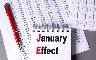 JANUARY EFFECT text on notebook with pen, calculator and chart on grey background
