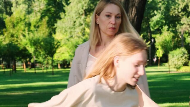 Teenage daughter yells arguing with mother in sunny park. Little girl runs away frustrated by mother misunderstanding