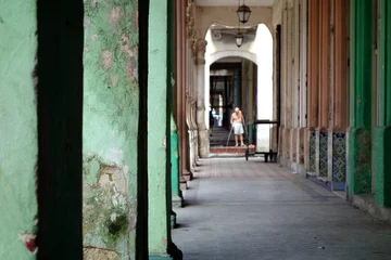 Türaufkleber Street life in Havana, old broken building with a man in the backround © Sabrina