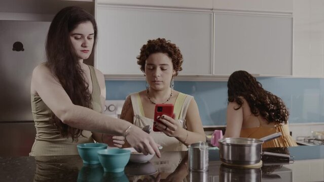 Mulheres na cozinha usando um smartphone para conferir uma receita. Cinematografico 4k.