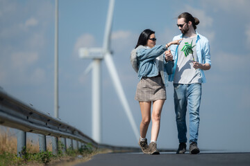 Young couple relaxing by the wind turbine on the lake