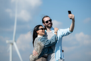 happy young couple taking selfie with smartphone in front of windmills - Powered by Adobe