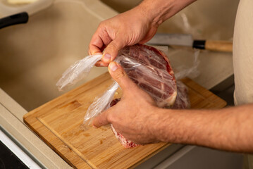 male hands unpack portioned raw frozen meat from polyethylene