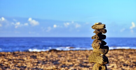 Pyramid of stones by the sea at dawn. Balanced zen stones on the beach of El Cotillo in Fuerteventura, Canary Islands, Spain