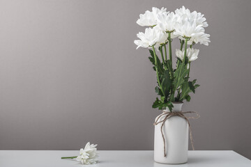 A bouquet of white chrysanthemums, daisies in a white ceramic vase on a white table. Postcard, home interior.