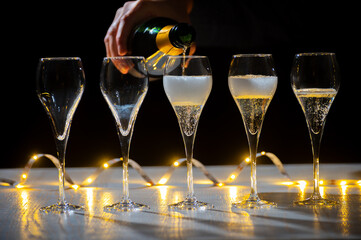 New year party, pouring of brut champagne bubbles cava or prosecco wine in tulip glasses with...