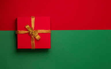 christmas red gift box, golden bow on the red and green background. New Year concept. Winter holidays and presents. Surprise delivery
