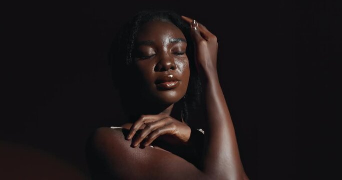 Face, hands and skincare with a natural black woman on a dark background in studio for feminine wellness. Arms, beauty and spa with a confident young model touching her body or skin in satisfaction