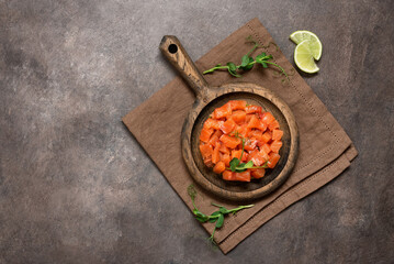 Raw salmon tartare with avocado served in culinary ring on dark rustic background. Top view, flat...