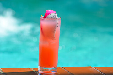  A glass of cold pink juice with passion fruit and ice on blue blurry background. 