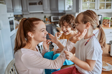 Mother and children having fun with chocolate in the kitchen