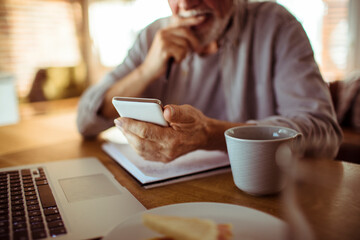Close up senior man using smartphone at home