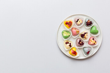 Plate with different chocolate on colored background. Assortment of fine chocolates top view vith copy space Health and obesity concept