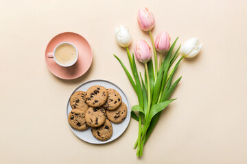 Cup of coffee mug with coffee, cookies and tulips on a colored background. Greeting spring card top...