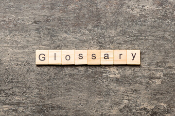 Glossary word written on wood block. Glossary text on cement table for your desing, Top view concept