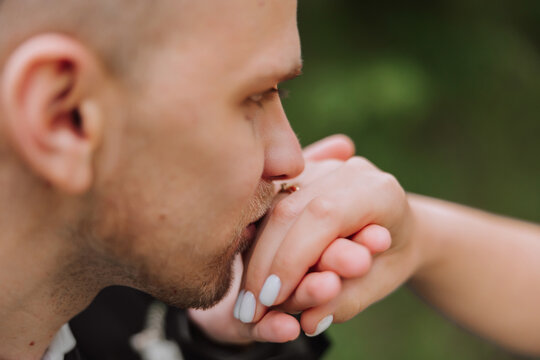 The groom kisses the hand of the bride. Cropped photo. In essential details. Tenderness