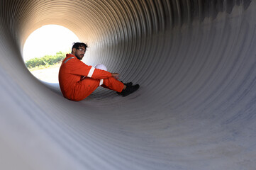Smart engineer with safety suit holding walkie-talkie inspecting large power system pipeline.
