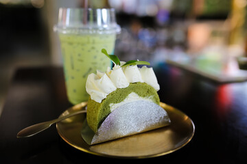 Cream cheese cake with green tea on wood plate in coffee shop.