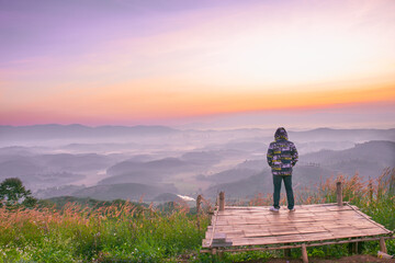 A man standing on the top of the mountain and looking at sunrise.