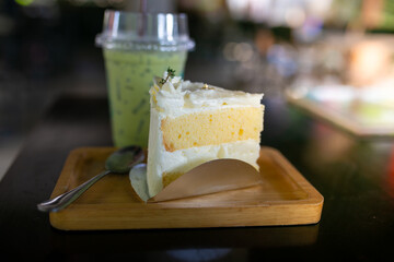 Cream cheese cake with green tea on wood plate in coffee shop.