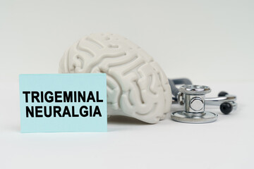 On a white surface next to the brain there is a stethoscope and stickers with the inscription - Trigeminal neuralgia