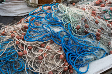 A set of fishing nets piled up on a fishing boat after a fishing trip. Nets joined by colored ropes with floats attached.