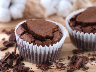 Gluten free chocolate brownies lying on a wooden surface with chocolate near them.