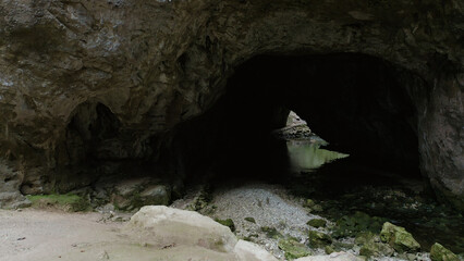 Obraz premium A hidden world of wonder and tranquility, the cave reveals the timeless beauty of nature's relentless erosion amidst the solid embrace of earth and rock, with the gentle melody of a river as its soun