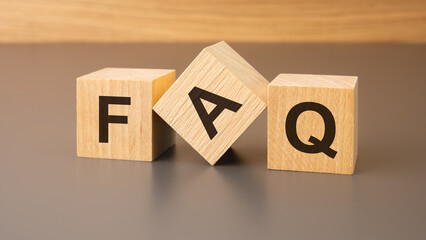 three wooden blocks on a brown background, with the abbreviation FAQ - Frequency Asked Questions