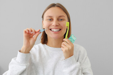 woman with white teeth holds dental floss, toothbrush and interdental brush to for prevent oral...