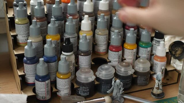 putting paint bottle on stand painting minis, miniatures for rpg game