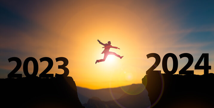 New Year 2024 concept.Businessman jumping on cliff 2024 over the precipice at amazing sunset.Reopening for business and lifestyle,new normal,challenge,career path,change,starting,readiness of leaders