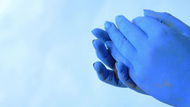 Blue painted hands holding sea turtle with blue background and copy space