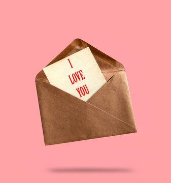 Vintage kraft paper evelope with paper sheet with inscription i love you on pink background. Love letter concept.