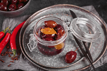 Marinated plums with spices in glass jar on the kitchen table. Homemade canning. Vegetable snack for winter.