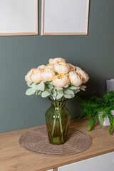 Artificial flowers for the interior. Bouquet of yellow peonies in a glass vase. Flowers in living room or bedroom