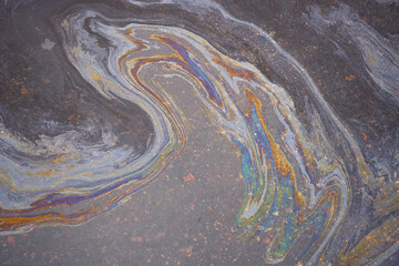 A marble texture of a rainbow spill of gasoline on a sidewalk in a puddle as a background.