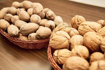Pecans and walnuts on the table in a wicker basket.
