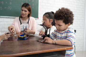Happy African American kid boy studying with electric robot and friend in classroom
