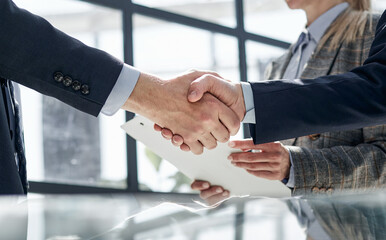 Two business people shaking hands in front of their colleagues