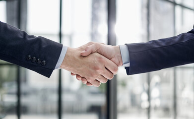 executives shaking hands in front of their manager and a colleague