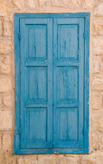 Weathered, old, blue, painted wooden shutters on a stone building in Safed, Israel
