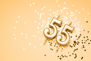 55 years celebration festive background made with golden candle in the form of number Fifty-five lying on sparkles. Universal holiday banner with copy space.