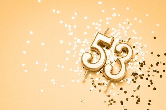 53 years celebration festive background made with golden candle in the form of number fifty-three lying on sparkles. Universal holiday banner with copy space.