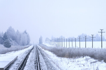 Panoramic winter view of a single-track snow-covered railroad going off into the distance.