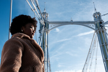 Young black woman standing under historical London bridge.