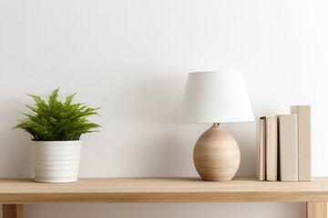 Table lamp, books, plant in a bright interior against a white wall.