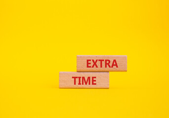 Extra time symbol. Concept word Extra time on wooden blocks. Beautiful yellow background. Business...