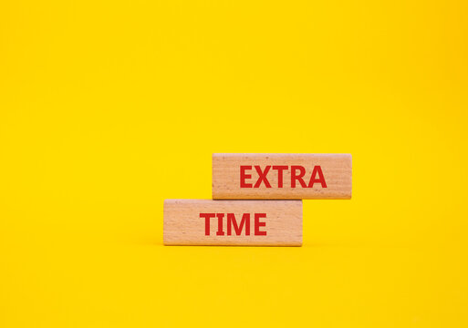 Extra time symbol. Concept word Extra time on wooden blocks. Beautiful yellow background. Business and Extra time concept. Copy space