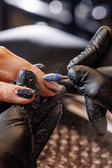 Manicurist doing hardware manicure to female client using special tools